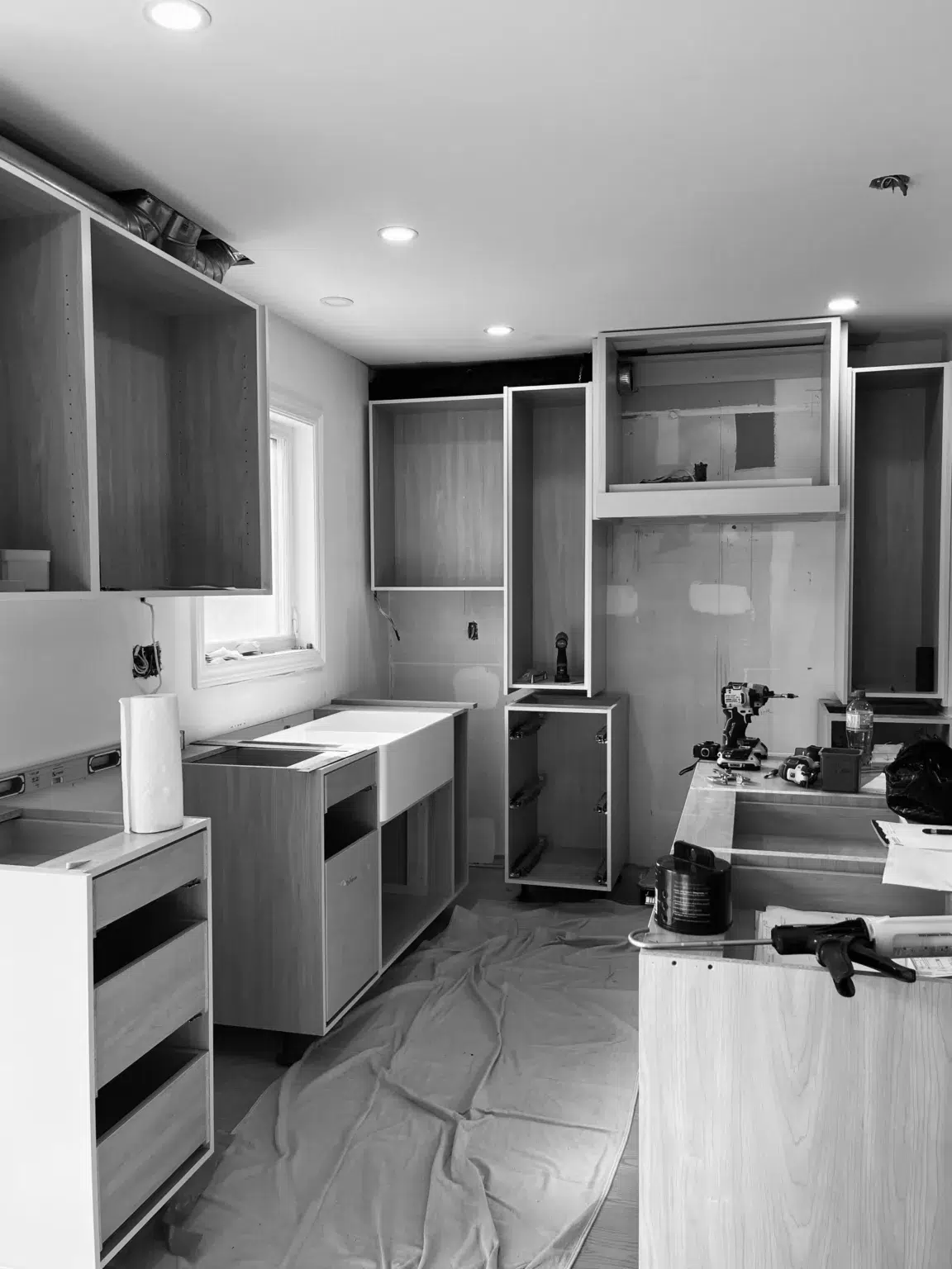 A kitchen installation in progress, featuring cabinets without doors and designated spots for lighting.