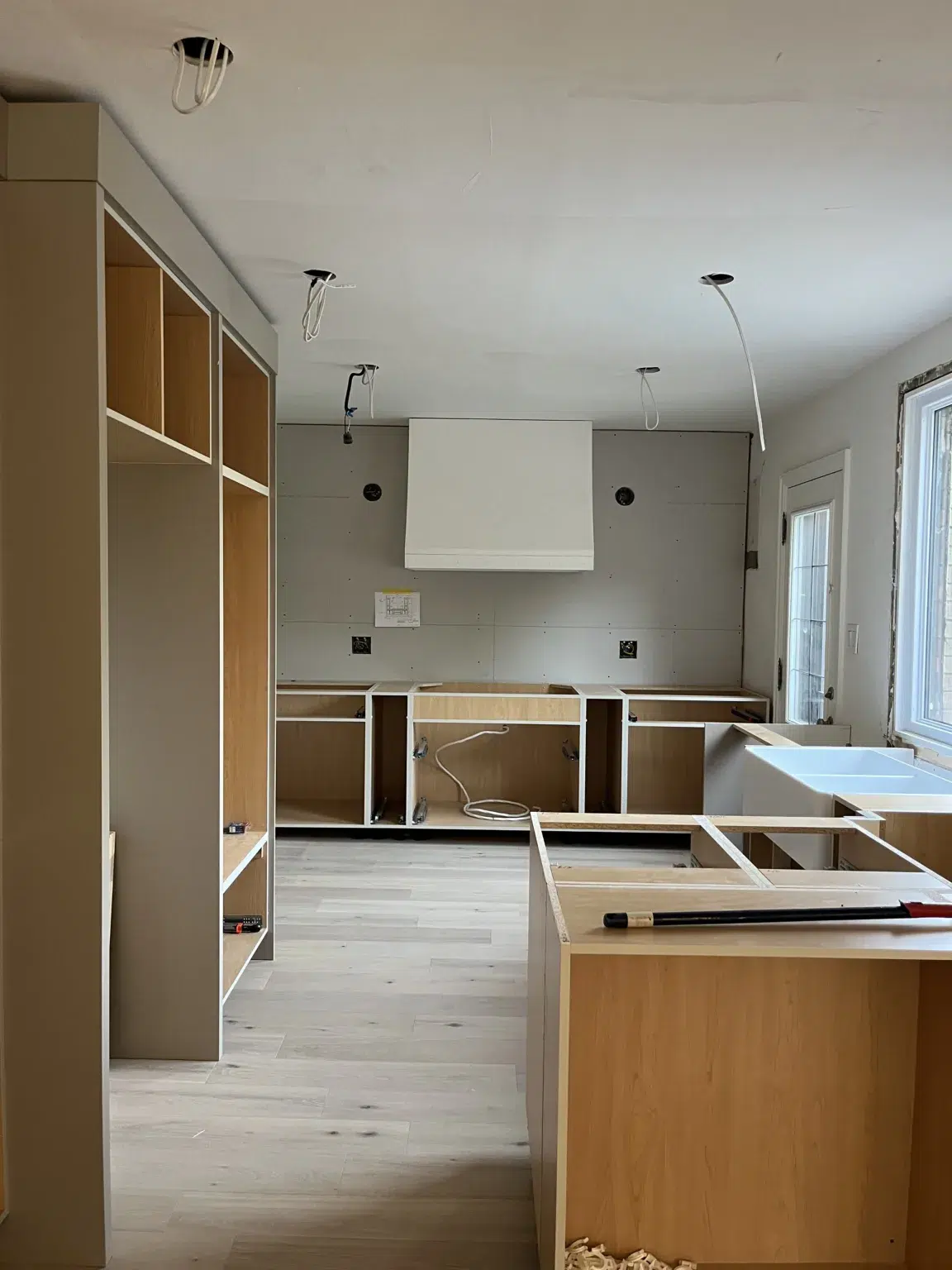 A kitchen installation in progress, featuring cabinets without doors and designated spots for lighting.